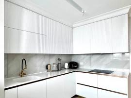 Белая кухня с рифлеными фасадами под потолок и тонкой столешницей